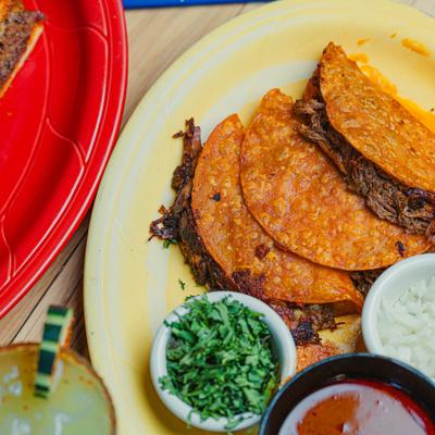 Quesabirria tacos platter with cilantro, onions, and dipping broth.