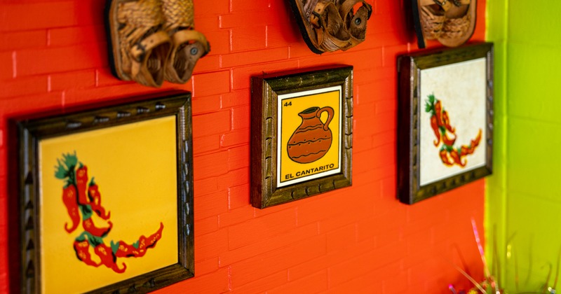 Framed pictures and woven leather footwear on the wall