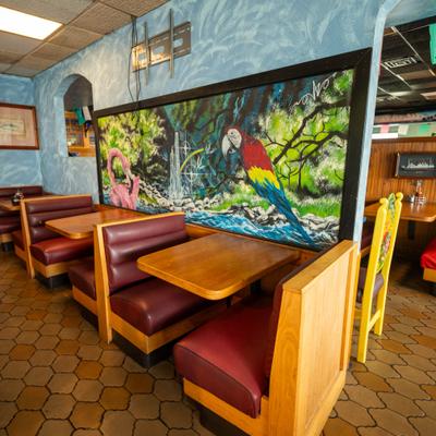 Interior featuring vinyl booths, wooden tables, textured blue walls, and a large mural.