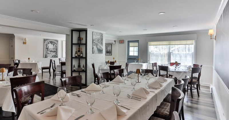 Interior, white cloth tables for ten, six and four people, wine shelf, back entrance