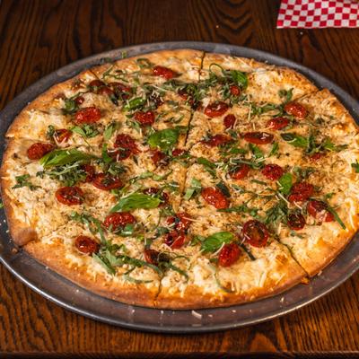 Vegan Margherita pizza on a round metal plate atop a wooden table.