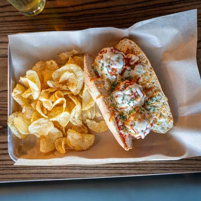 The Baller, Italian meatball sandwich, served with potato chips.