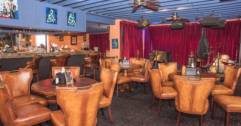 Cozy interior seating area with upholstered chairs, bar, and music stage