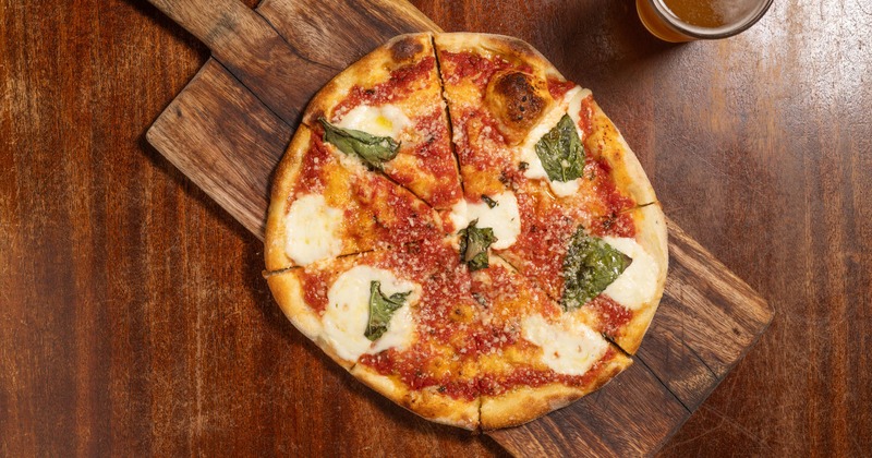 Margarita pizza paired with beer on table, top view
