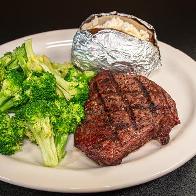 Grilled steak served with broccoli and loaded baked potato.