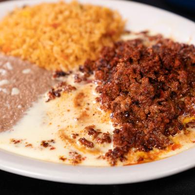 Chori Pollo with melted cheese sauce and sides of rice and refried beans.