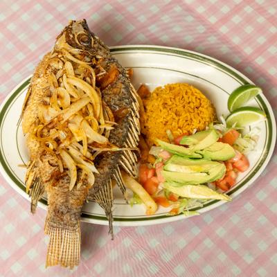 Fried tilapia platter with sides of rice, salad, and lime wedges.