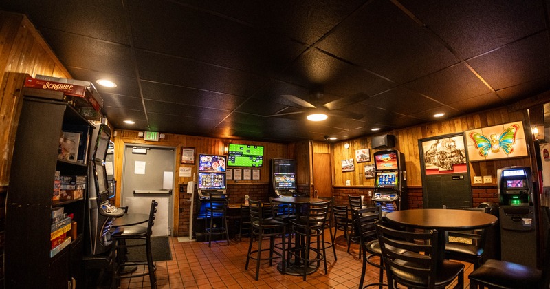 Cozy room with gaming machines, high tables, board games, and neon signs