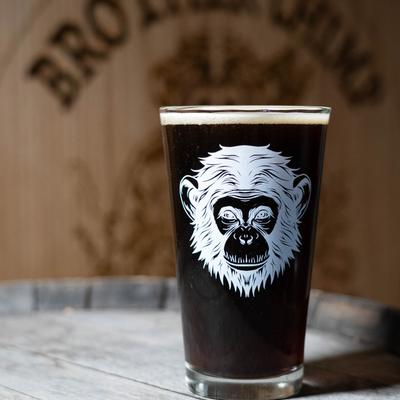 Dark beer in a glass with a chimp illustration.