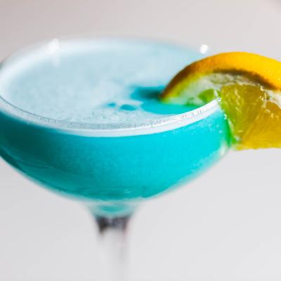 A close up of Blue Lagoon cocktail garnished with lemon wedge.