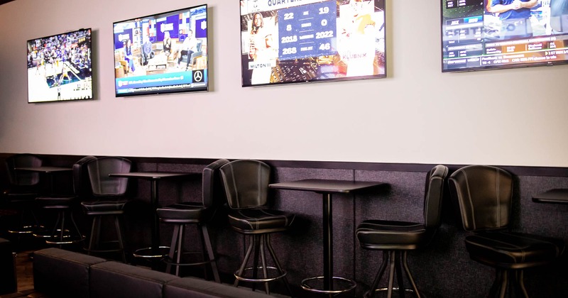 High tables and chairs for two, big Tv's on wall