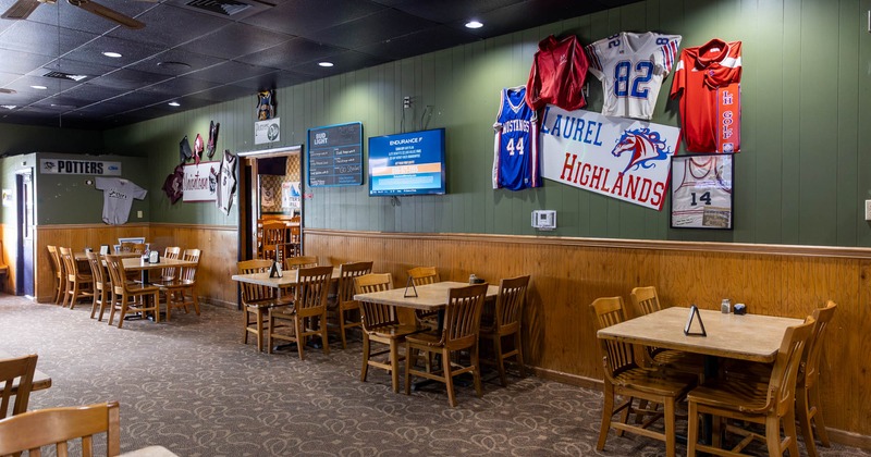 Spacious room with carpet flooring, dining tables and chairs, sports memorabilia on the walls