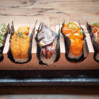 Assorted sushi pieces with uni, eel, and salmon roe in a wooden holder.