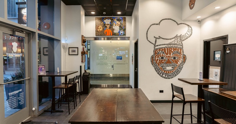 Interior featuring wooden tables and a chef-themed mural on the wall
