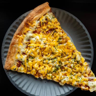 A slice of pizza with bacon, mozzarella, and cheddar cheese.