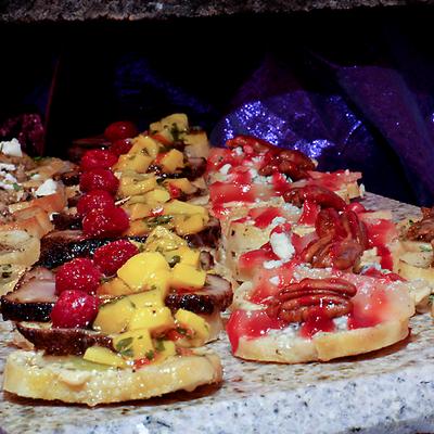 Gourmet crostini appetizers with mango salsa, raspberries, pecans, cheese, and berry sauce.