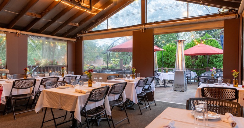 Interior and terrace view, tab;es and chairs set up for a diner