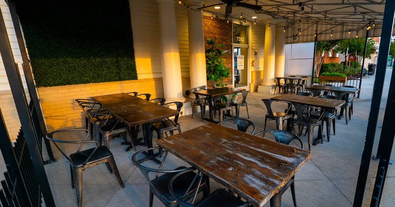 Outdoor dining area with wooden tables, metal chairs and string lights under a canopy