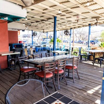 Covered patio with wooden flooring, tables, ceiling fans, and ventilators.