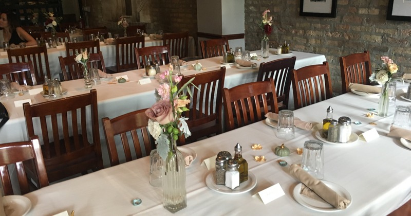 Interior, long tables adorned with white tablecloths, set with place settings and floral display