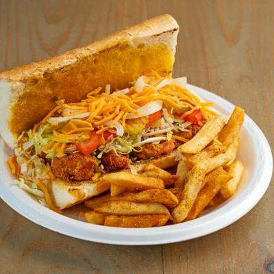 Shrimp Po Boy sandwich with lettuce, tomato, grated cheese and side of fries.