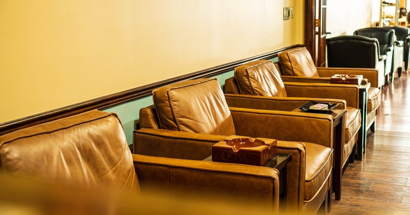 Brown leather armchairs arranged in a row with ashtrays in between