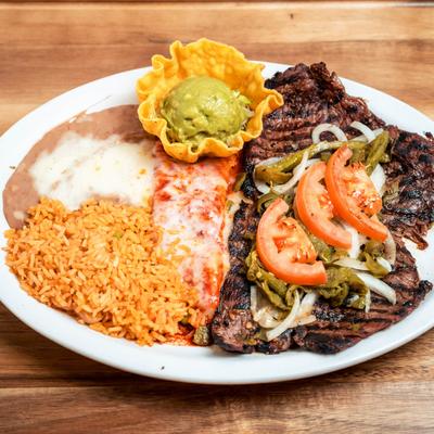 Grilled steak served with rice, beans, guacamole, and red cheese enchiladas.