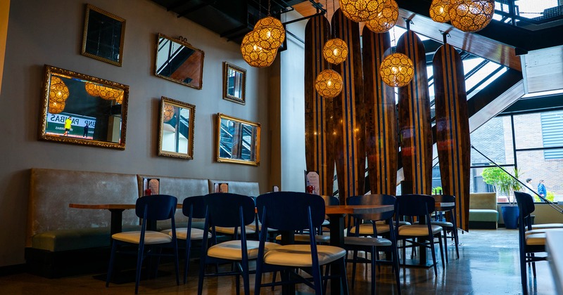 Interior, dining area, tables for four, padded banquette bench with tables, framed mirrors