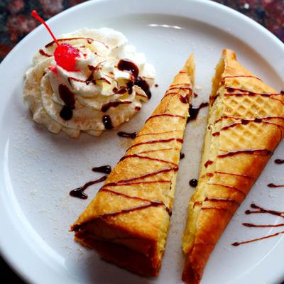 Fried cheesecake served with chocolate drizzle and whipped cream.