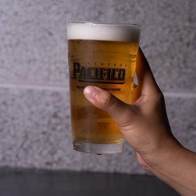 A hand holding a glass of light beer.