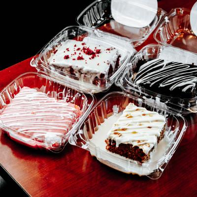 Assorted cake slices in clear plastic takeout containers.