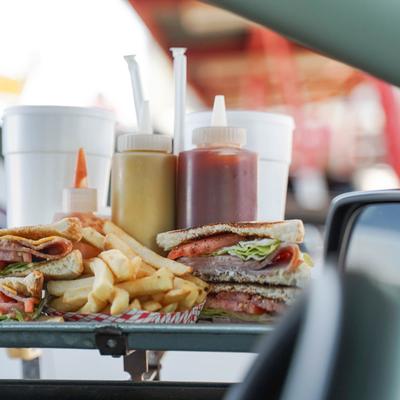 ham sandwiches and fries hanging on tray at a car.