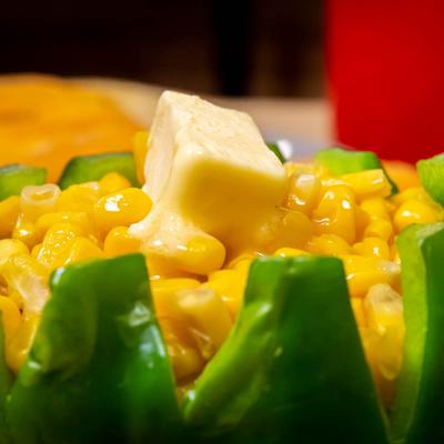 Corn served in a fresh pepper topped with a butter cube