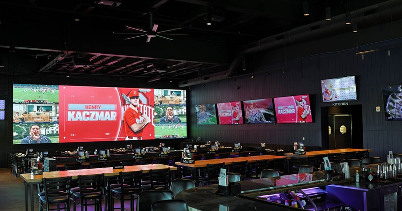 Interior - a large video wall displaying sports content, including a feature on "Henry Kaczmar."
