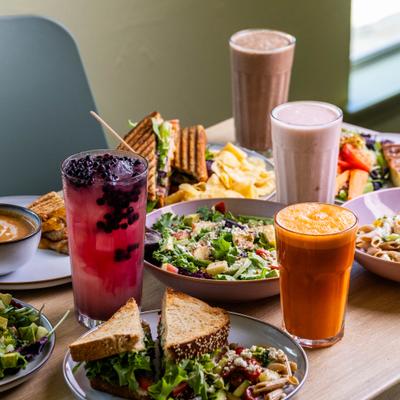 Brunch spread including grilled sandwiches, fresh salads and drinks served on the table.
