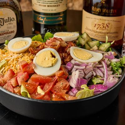 Fresh salad with cucumbers, tomatoes, red onions, boiled eggs, cheese, and bacon.