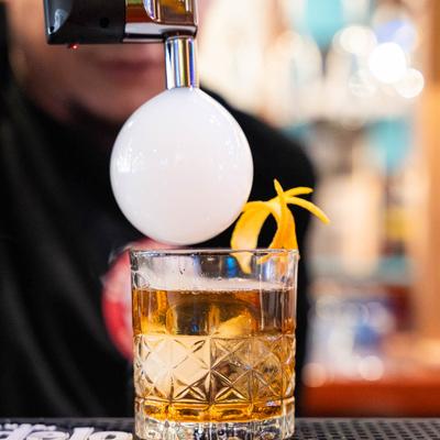 Flavor blaster being used to aplly the smoke bubble on top of the cocktail.