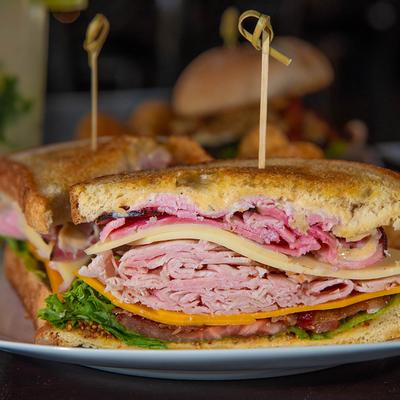 Club sandwich, with ham, turkey, smoked bacon, Swiss, cheddar, lettuce, tomato, and mayo.