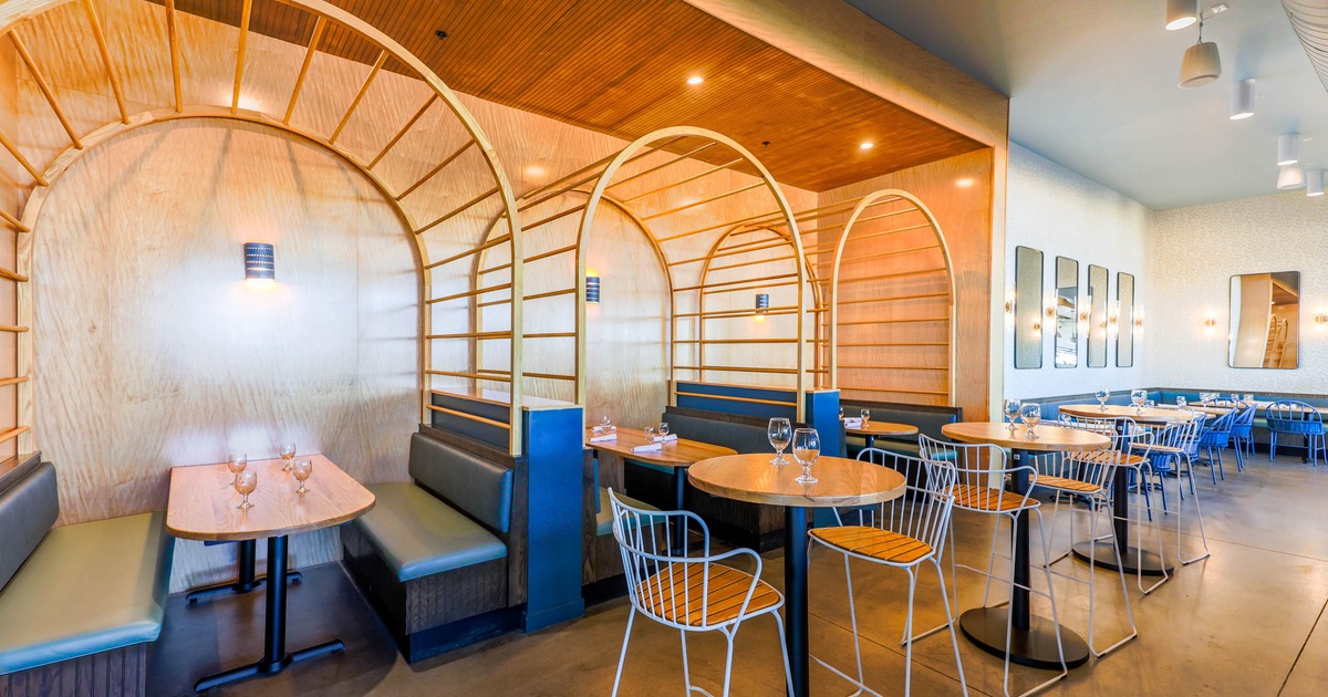 Interior, seating area with wooden arches, cushioned booths, and high-top tables