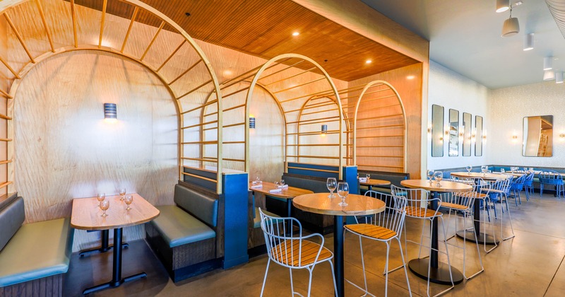 Interior, seating area with wooden arches, cushioned booths, and high-top tables