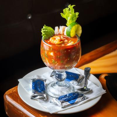 Shrimp cocktail served chilled in a glass goblet on a plate with saltine crackers.