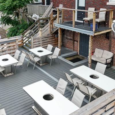 Outdoor dining area features white tables with built-in fire pits and matching chairs.