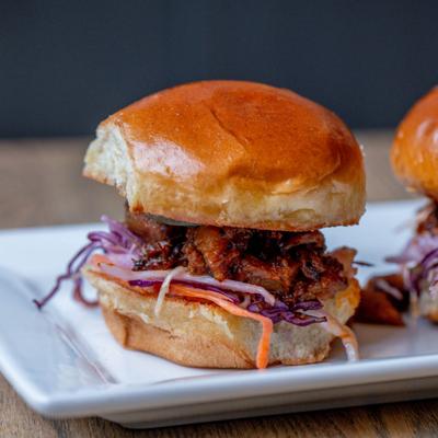 Brisket sliders with coleslaw arranged on a white plate.