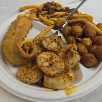 Fried seafood platter featuring fried fish, shrimp, fries and hush puppies.