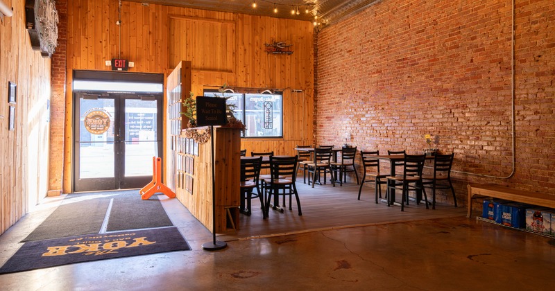Interior, bar entrance on the left, seating on the right, wood covered and brick walls