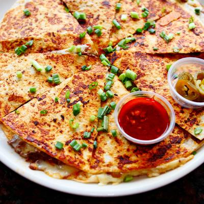 Pizza Birria topped with green onion and served with a dip and jalapenos.