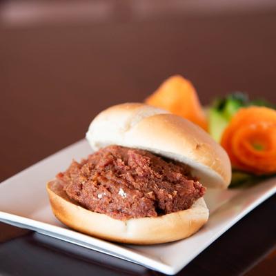 Minced raw beef sandwich served on a plate with veggie garnish.