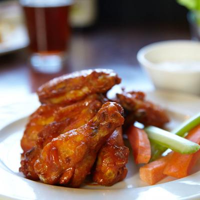 Chicken wings with a dipping sauce,  celery and carrots.