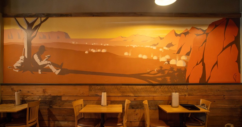 Interior, dining area, tables for two, large over the wall mural of prairie, wood coated walls