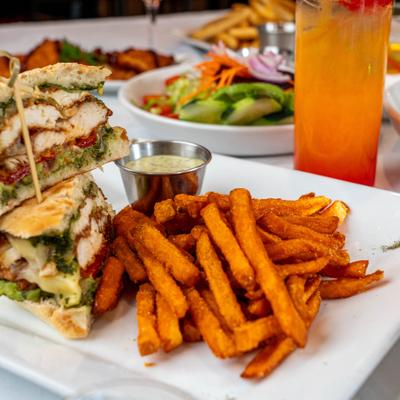 Fried chicken pesto panini served with other food and drinks on the table.